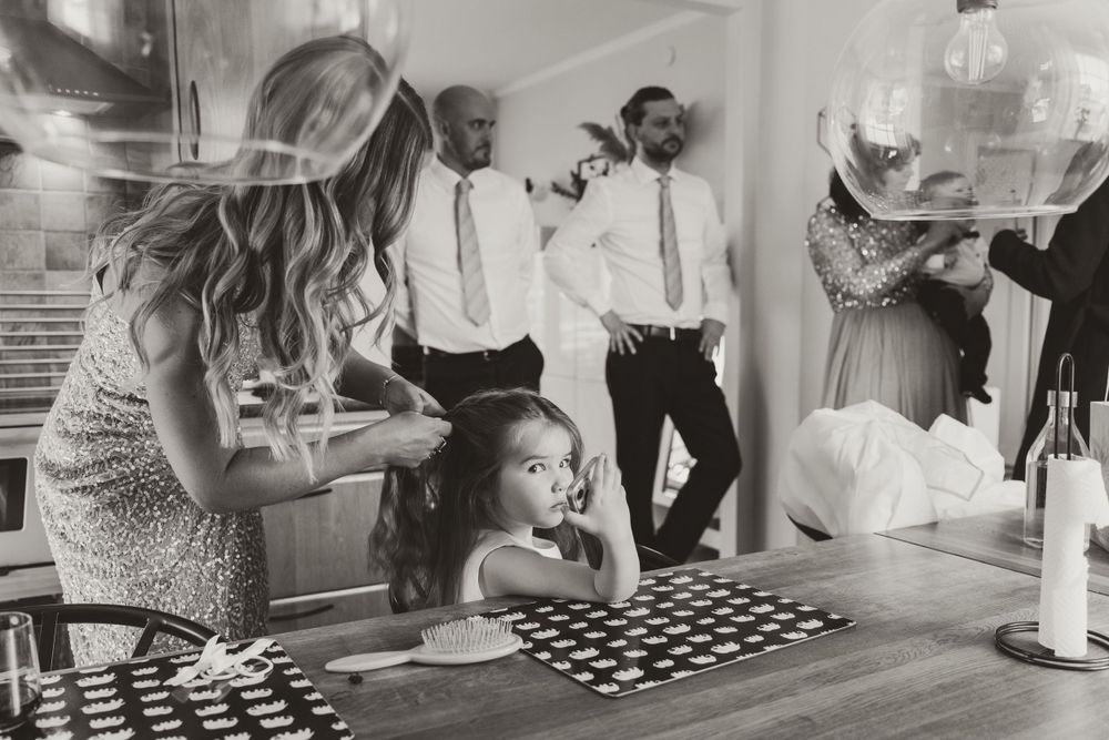 Black and white photo of wedding preparation activities around kitchen counter.