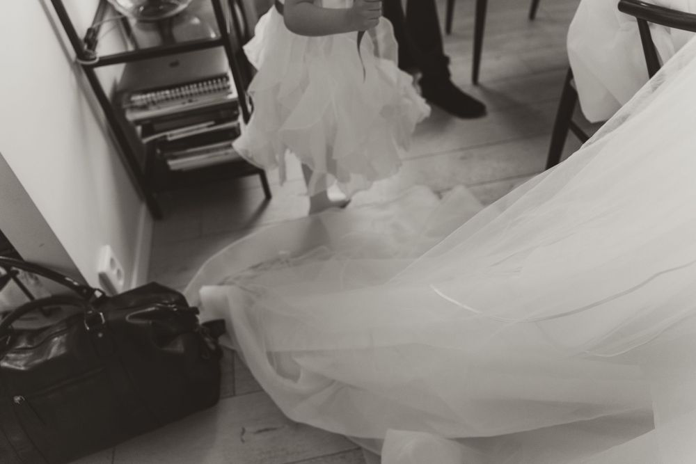 Artistic black and white shot of flowing wedding dress fabric on hardwood floors.