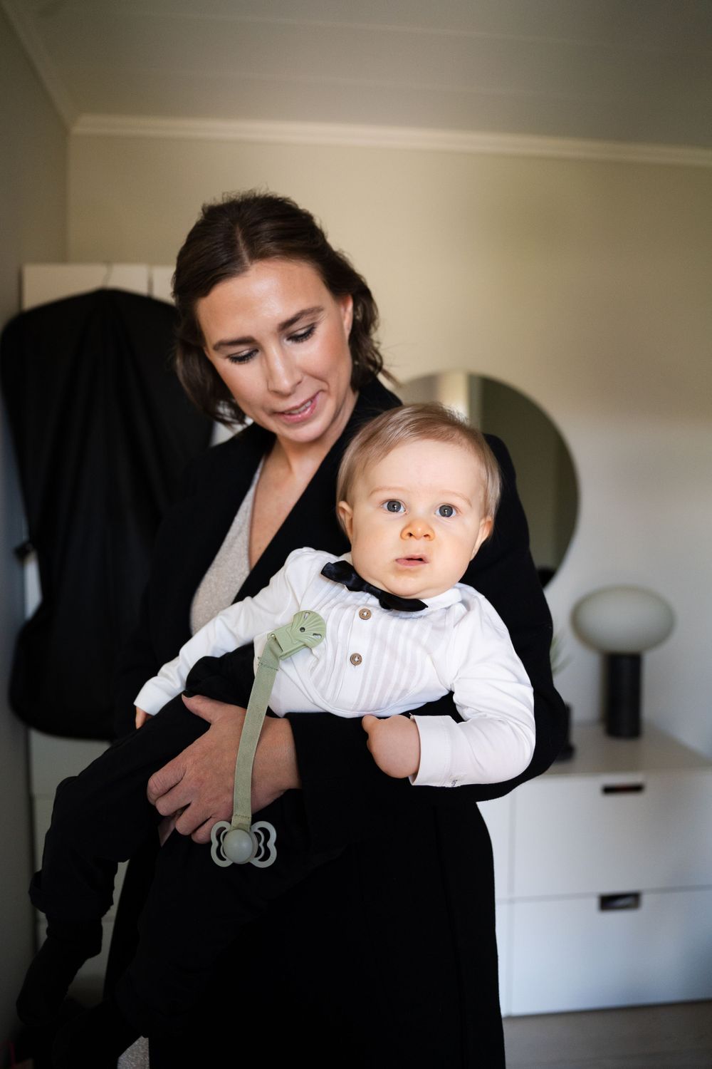 A formal wedding day preparation scene with infant in white outfit.