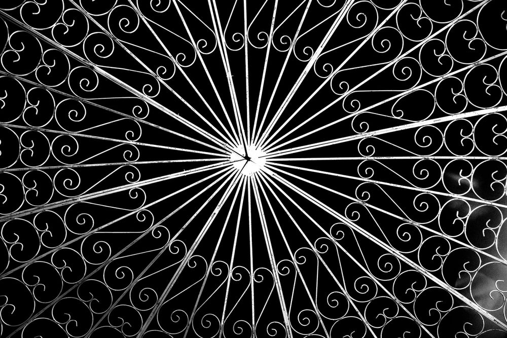 Intricate spiral ironwork pattern photographed in black and white.