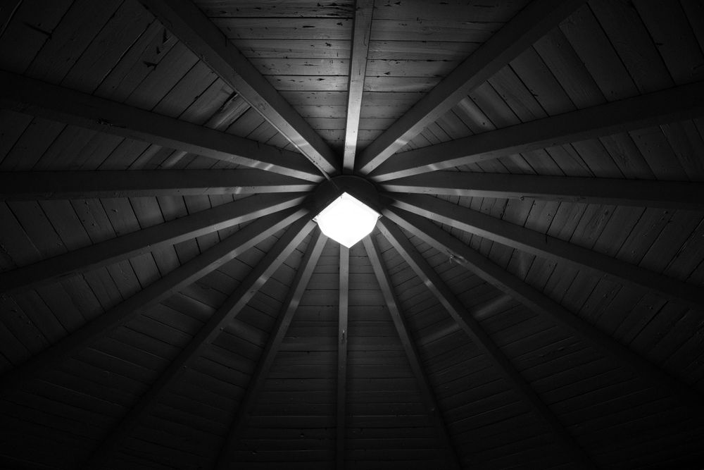 Geometric ceiling design with wooden beams radiating from a central light fixture.
