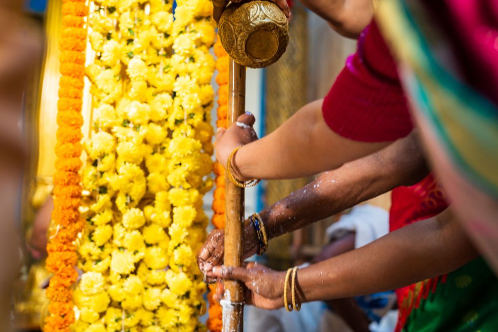 Close-up of hands arranging yellow marigold flower decorations at an Indian ceremony.