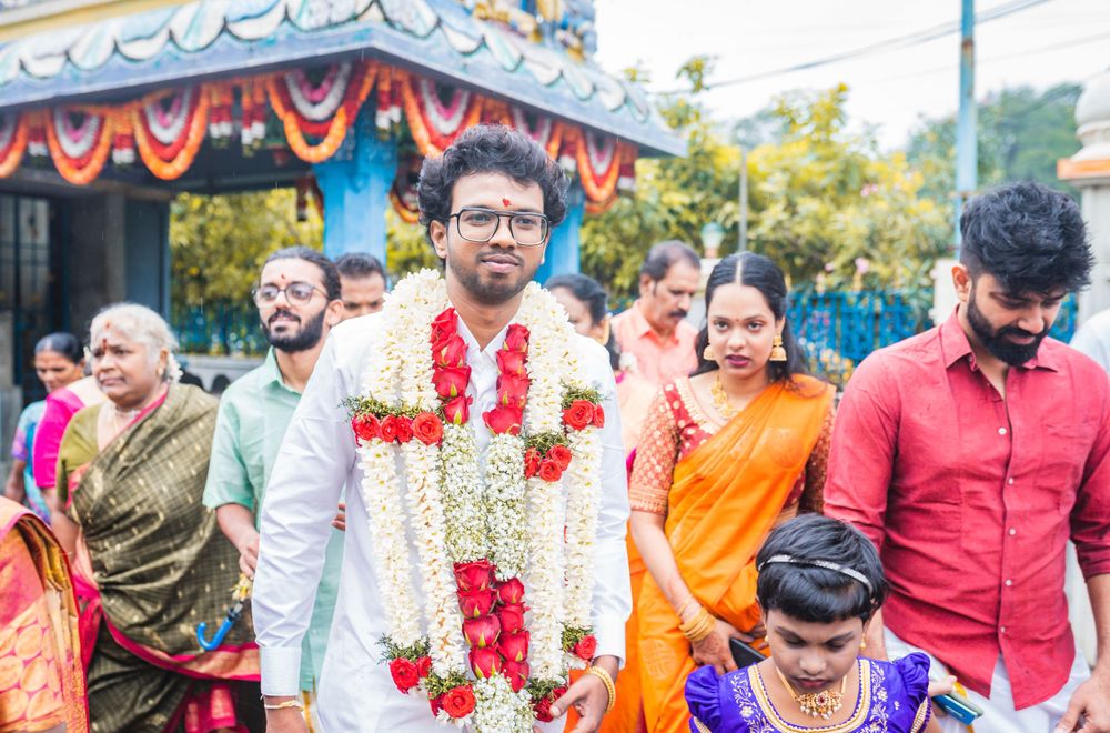 A traditional Indian wedding procession with guests wearing colorful saris and traditional attire walking outdoors.