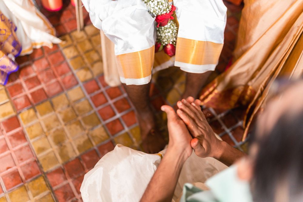 Close-up shot of hands during a traditional Indian wedding ritual on tiled floor.