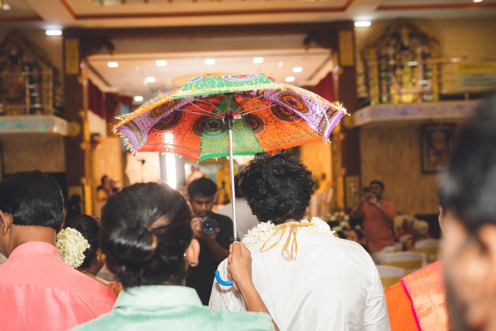 Decorative umbrella held during an indoor Indian wedding ceremony with soft lighting.