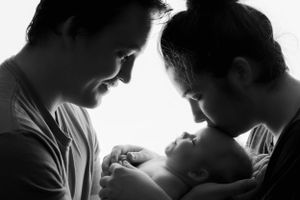 Parents kissing newborn baby on forehead in studio photoshoot