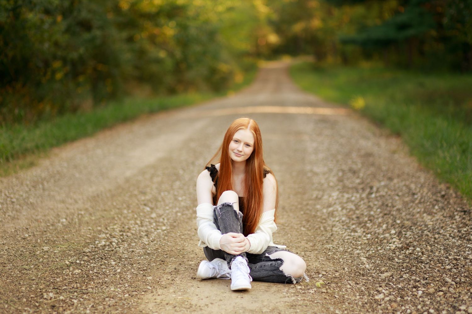Gorgeous red head senior poses on an old country rock road.