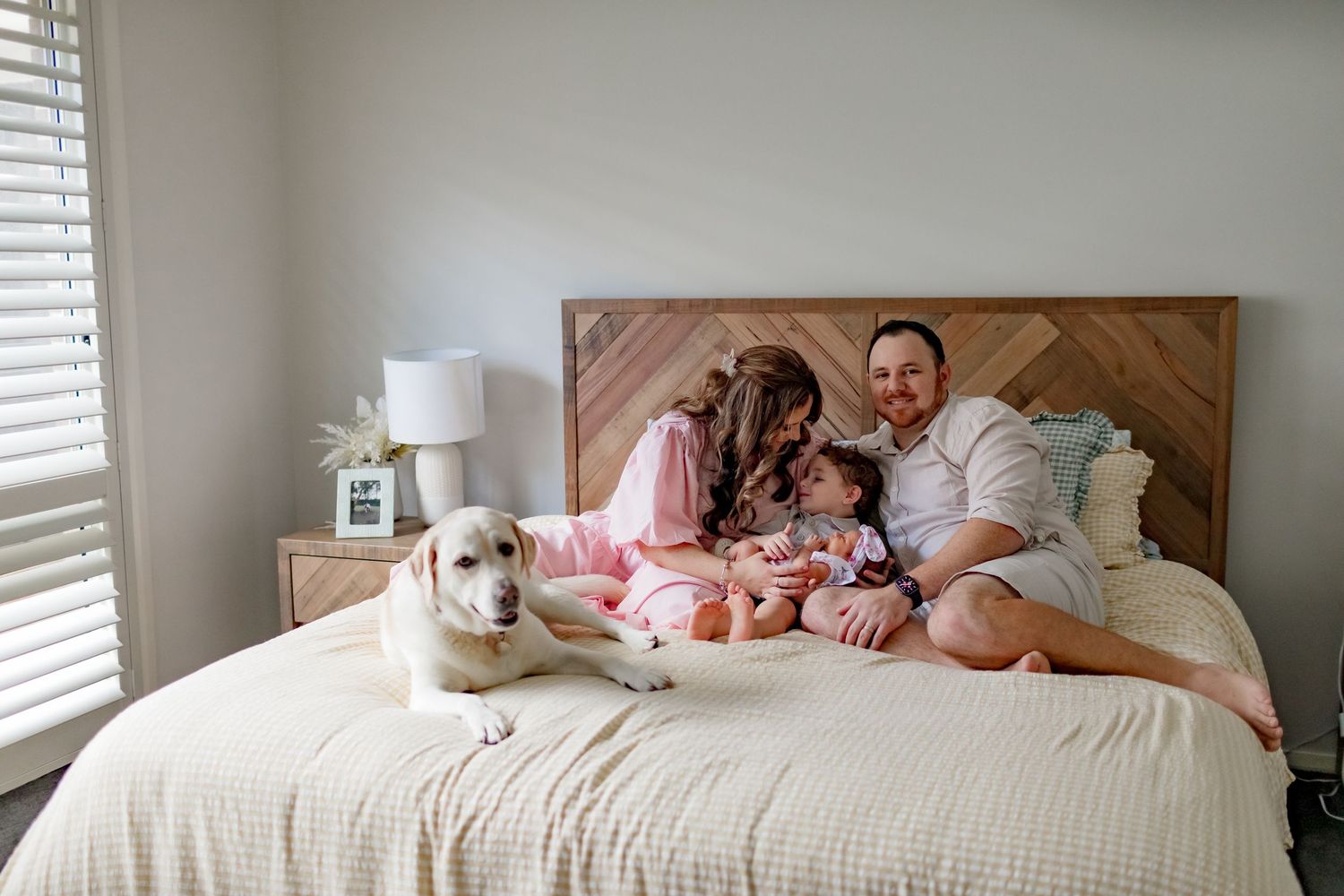 A family and their white dog share quality time together on a bed.