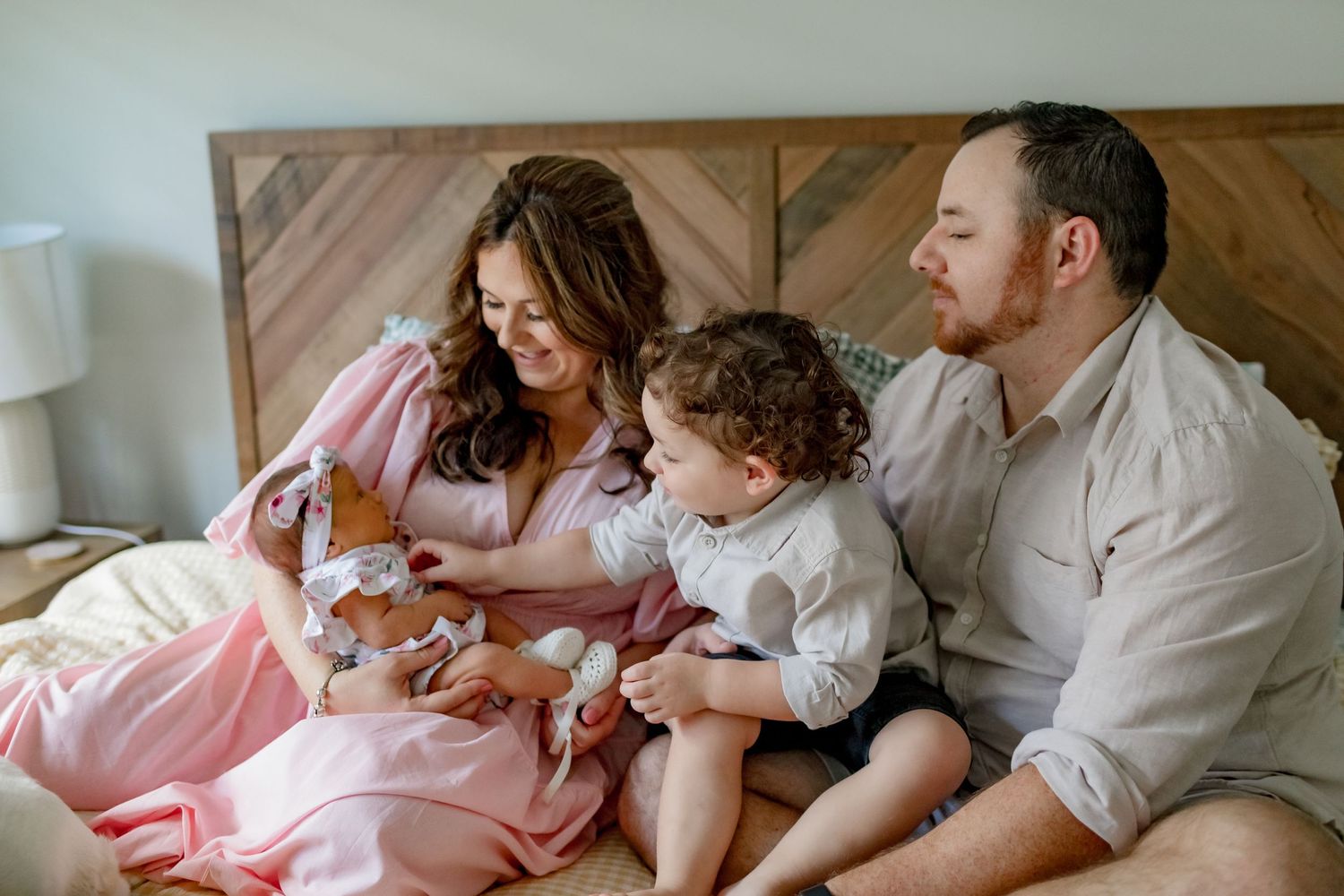 A family enjoying quality time together on a bed with wooden headboard.
