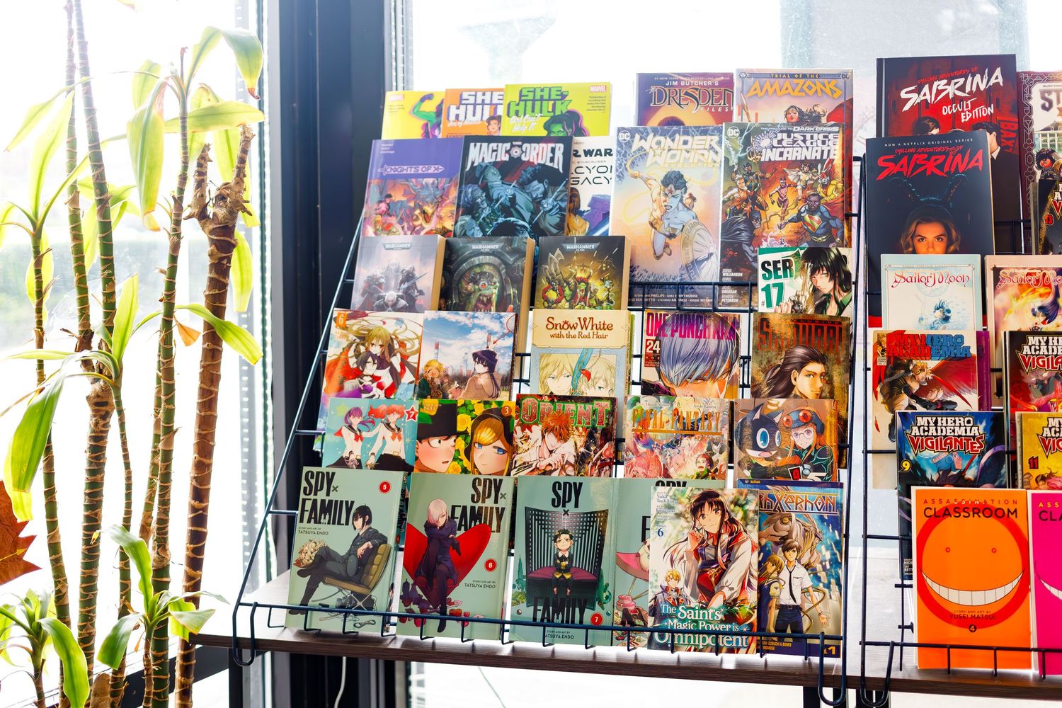 Wire rack display filled with diverse manga and graphic novels in a retail setting.