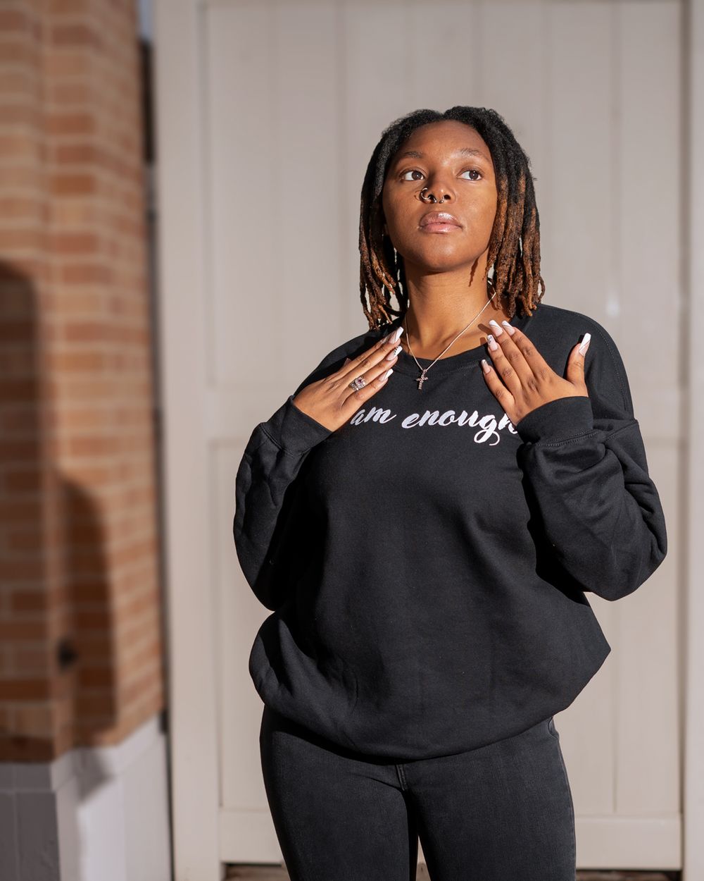 Black sweatshirt with white text photographed against light colored wall.