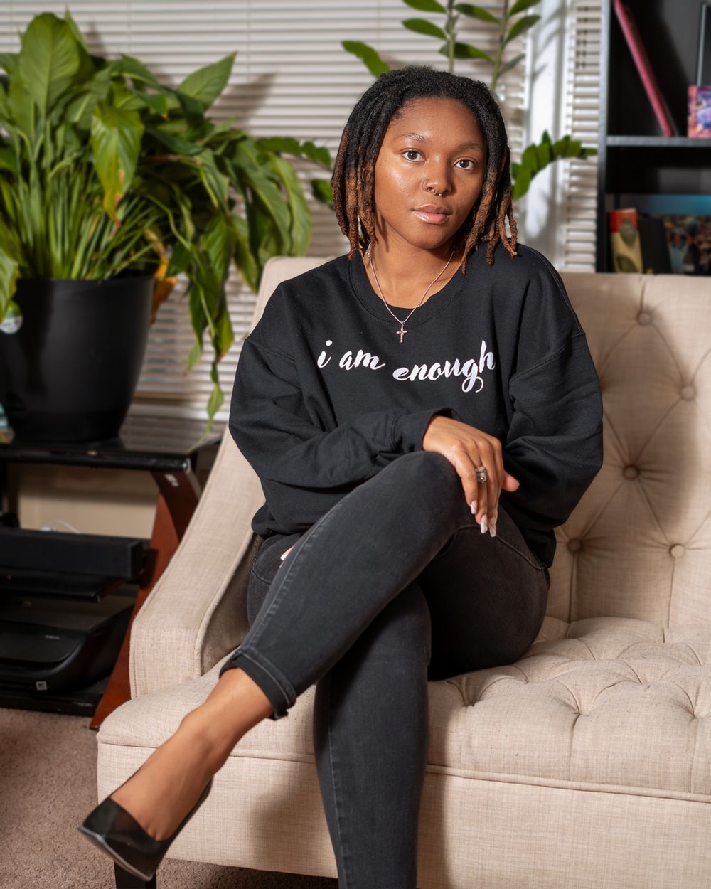 Casual black sweater with inspirational text styled with dark jeans in home setting.