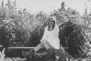 teen girl sitting in front of tall grass