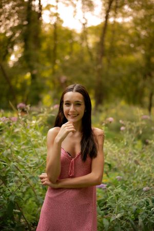 teen girl standing in the sunshine coming through trees