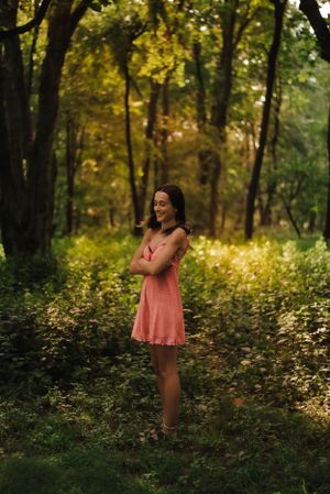 teen girl standing in the sunshine coming through trees
