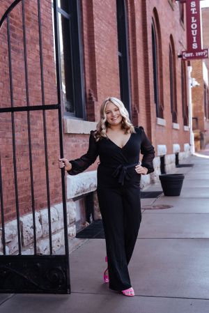 senior girl in black jumpsuit in front of brick building