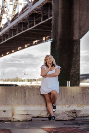 girl leans against concrete barricade under bridge
