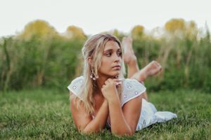 Teen girl in a white dress laying in the grass
