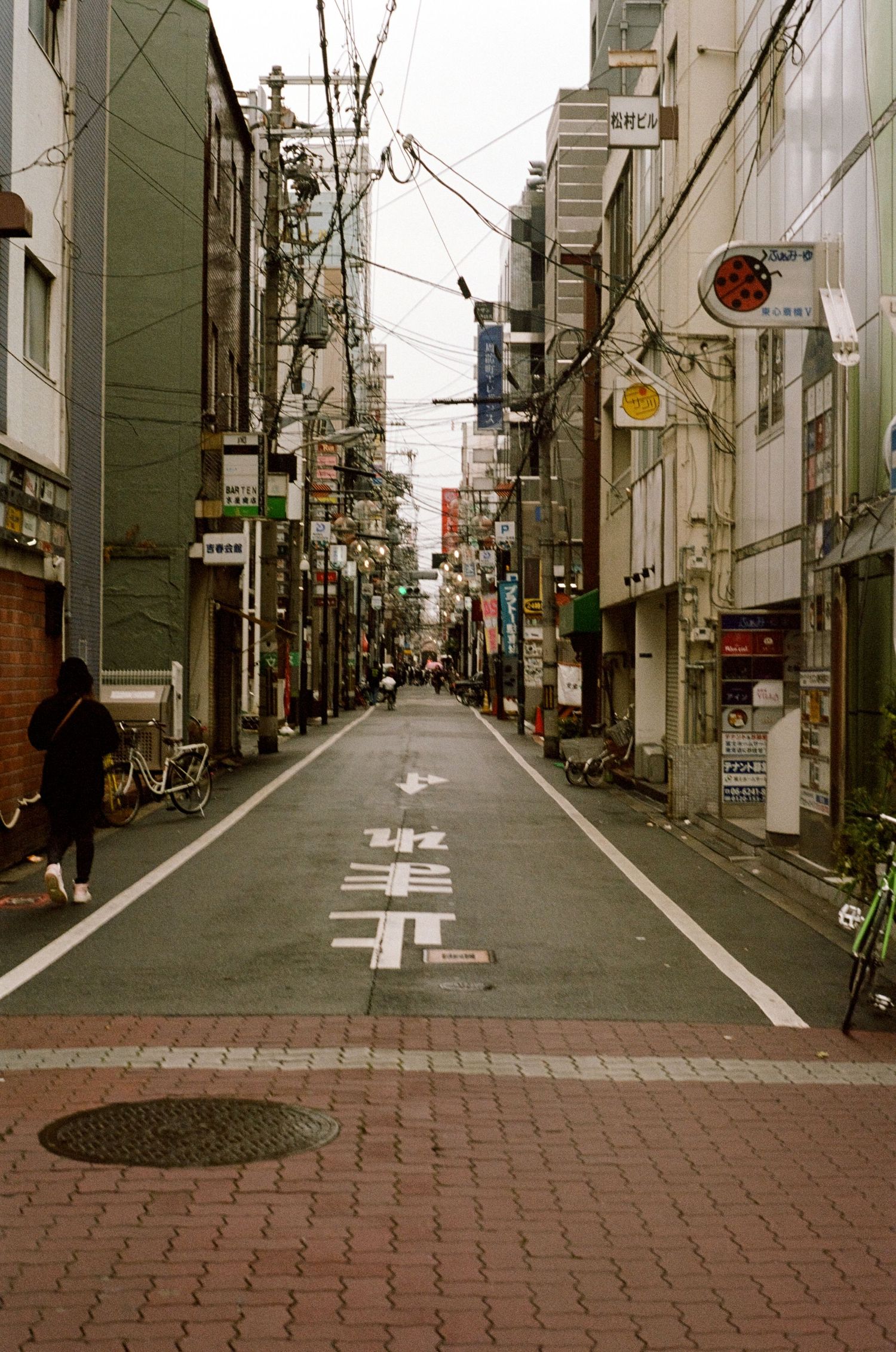 Urban alley in Japan with traditional architecture and utility poles creating leading lines.