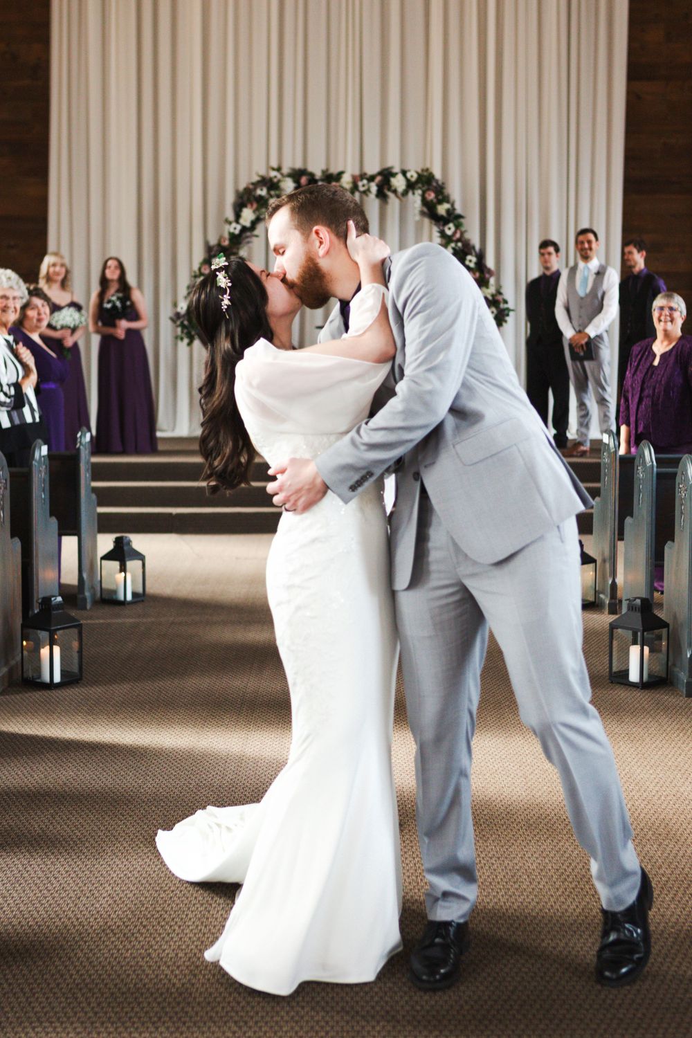 young couple kissing as they walk down the aisle of a church after getting married.