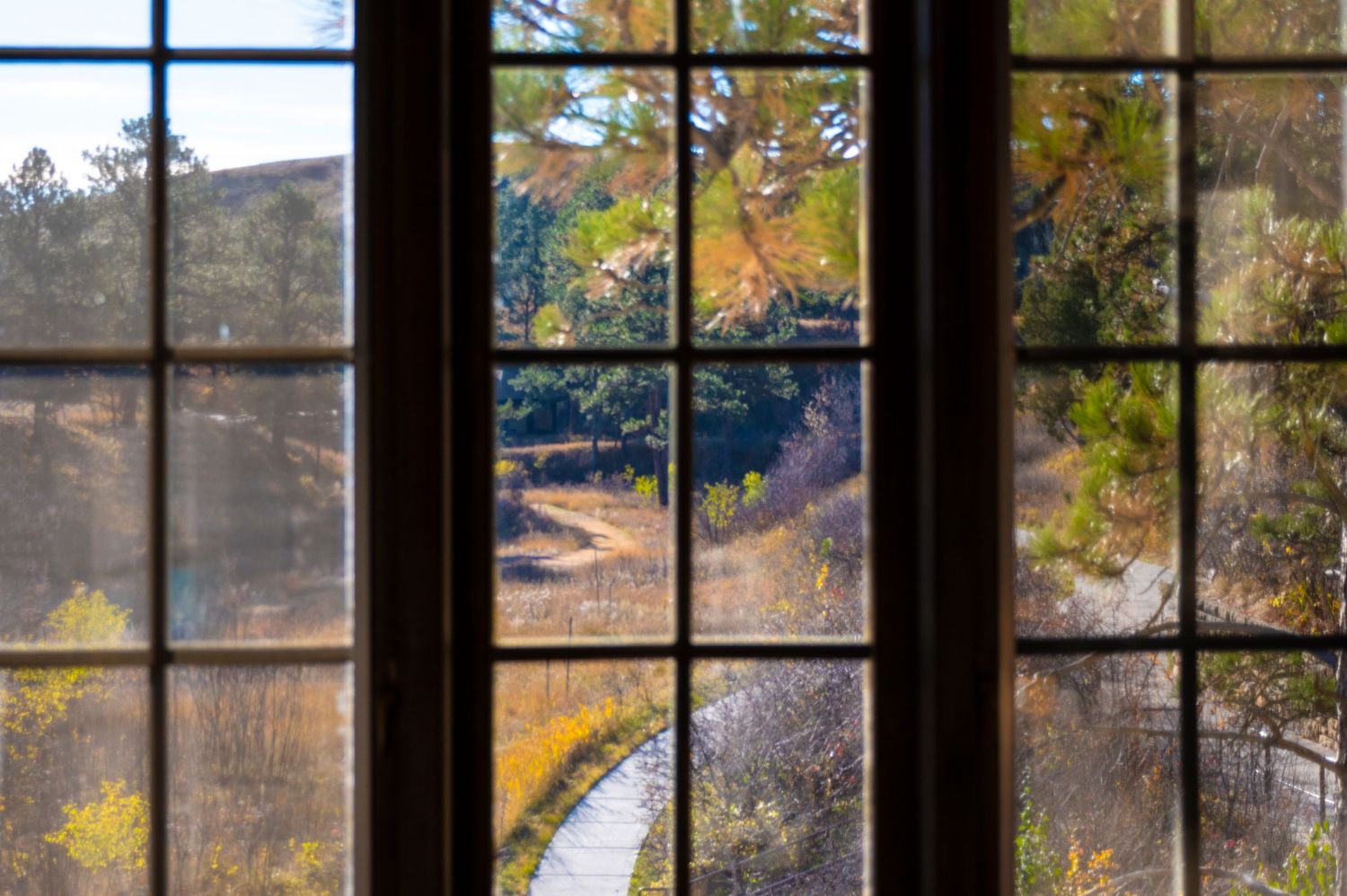 Window view of autumn landscape with mountains and trees through divided glass panes.