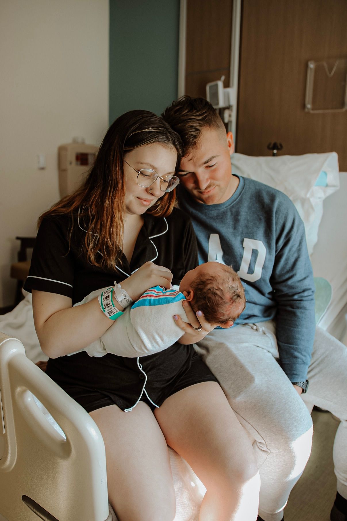 New parents bonding with their newborn baby in a hospital room.