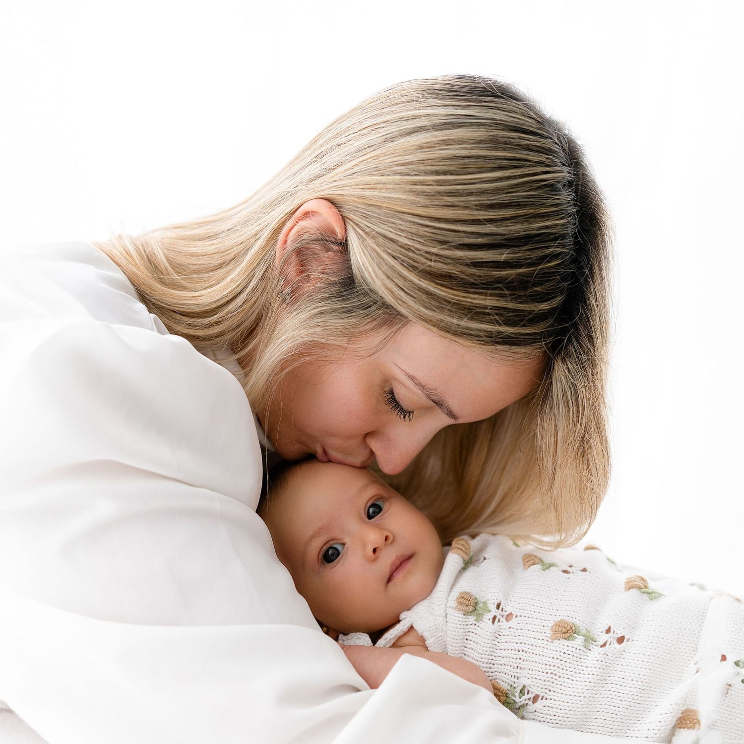 Tender moment captured between parent and baby on white background.