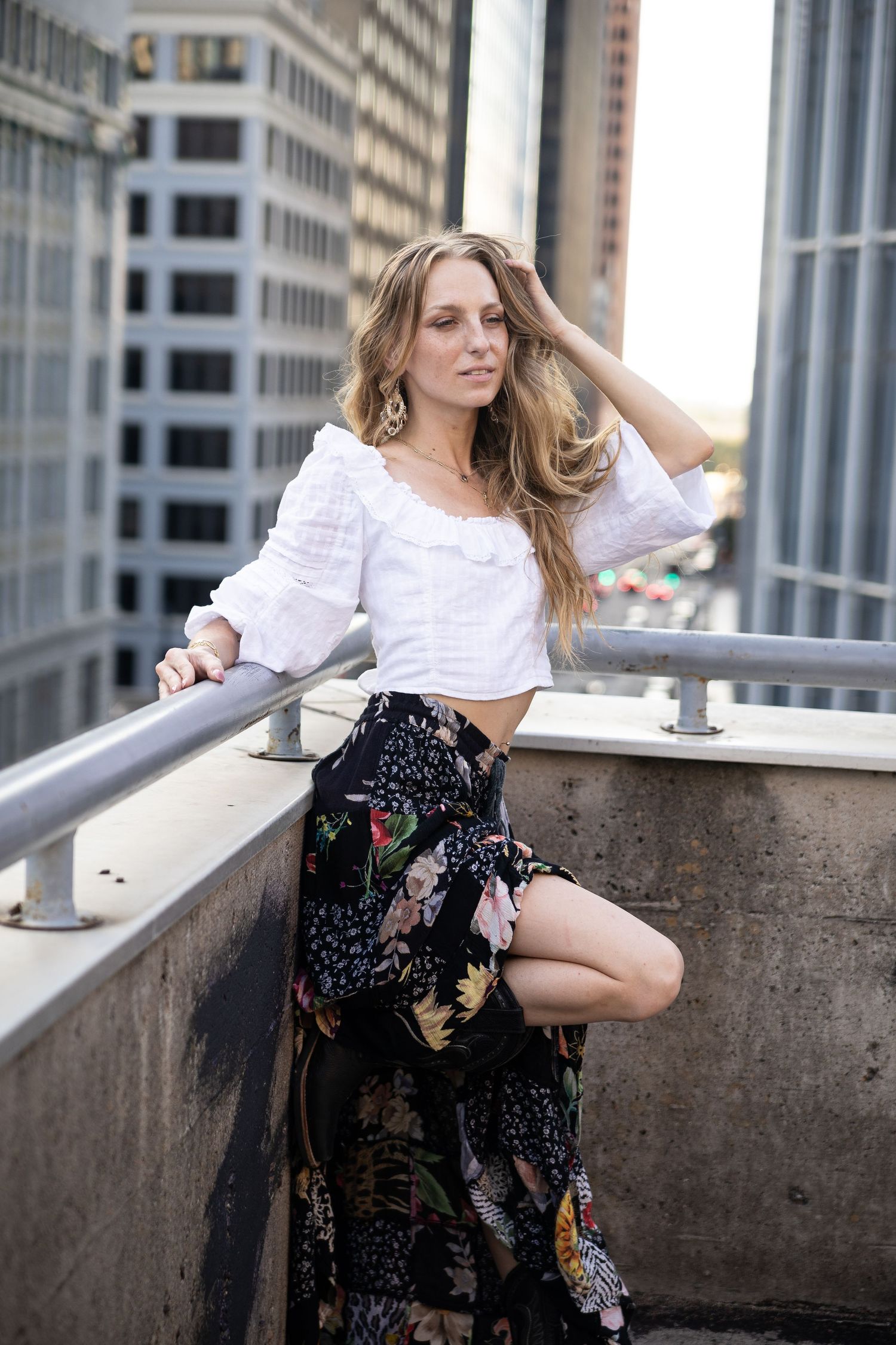 Artistic fashion portraits of a woman in a floral dress posing on a city rooftop.