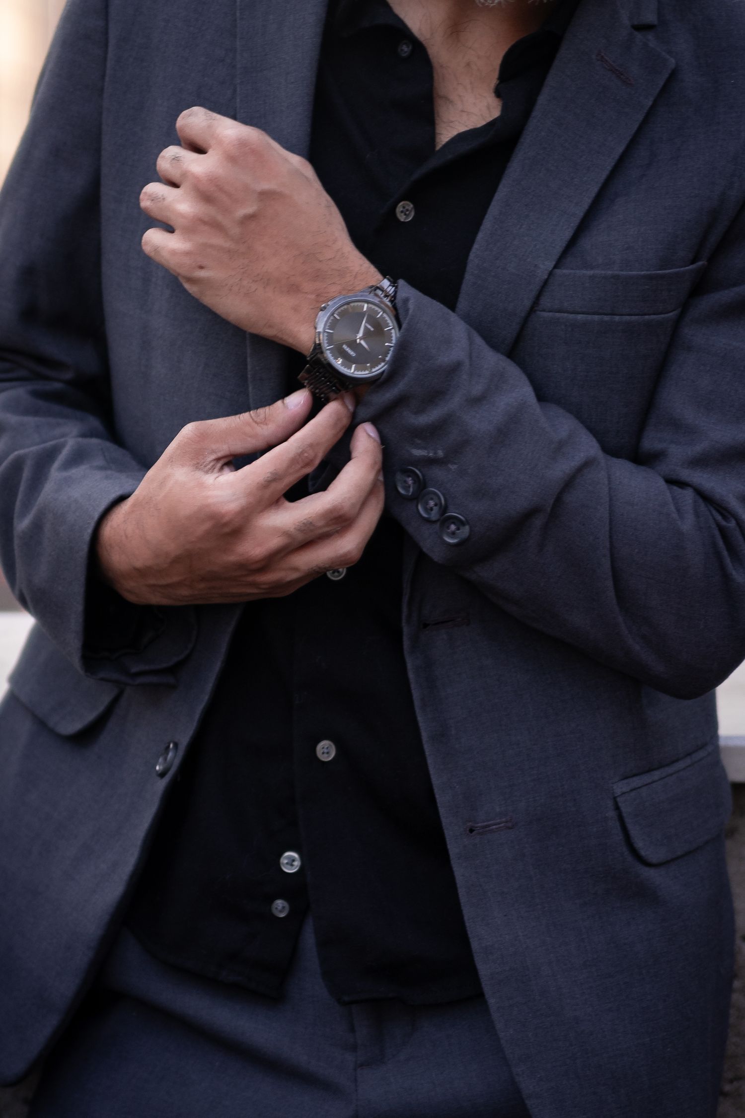 Close-up details of a man's suit and watch during an urban fashion photoshoot.