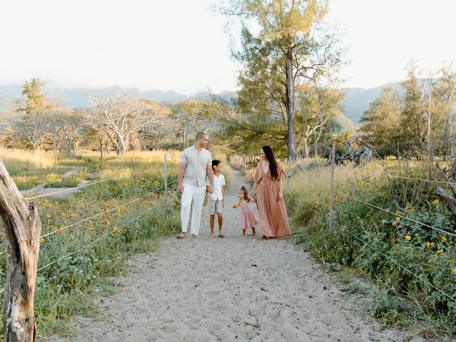 A family of four walking along a sandy path in the middle of foliage on Oahu in Hawaii