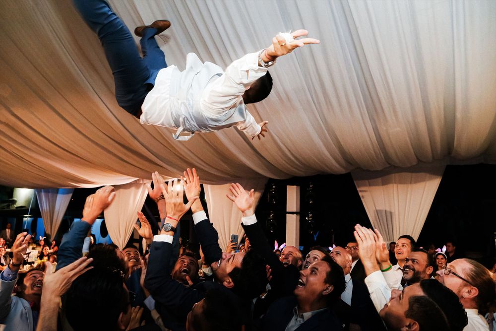 Wedding reception celebration under white tent with hands raised in excitement.