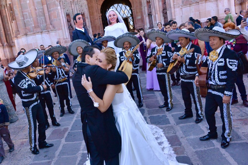 Newlyweds share a dance surrounded by mariachi band members in traditional attire.
