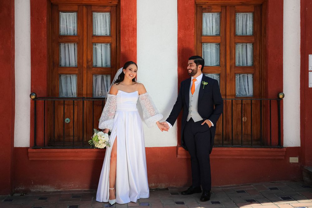 Wedding portraits taken against red wooden doors and white pillars.