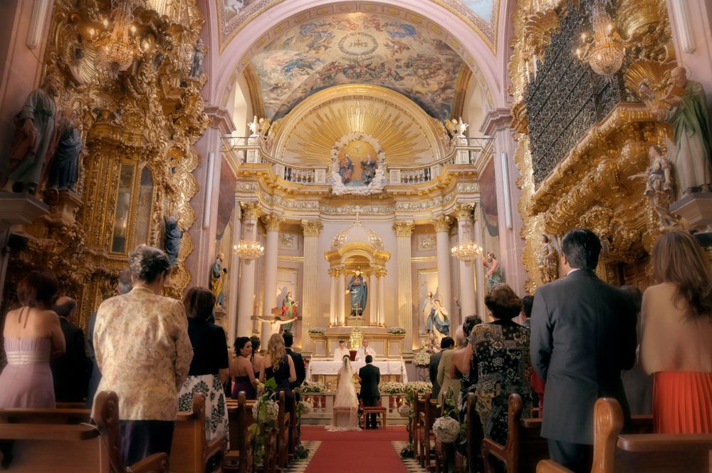 Ornate baroque church interior during a wedding ceremony with arched ceilings and gilded decorations.