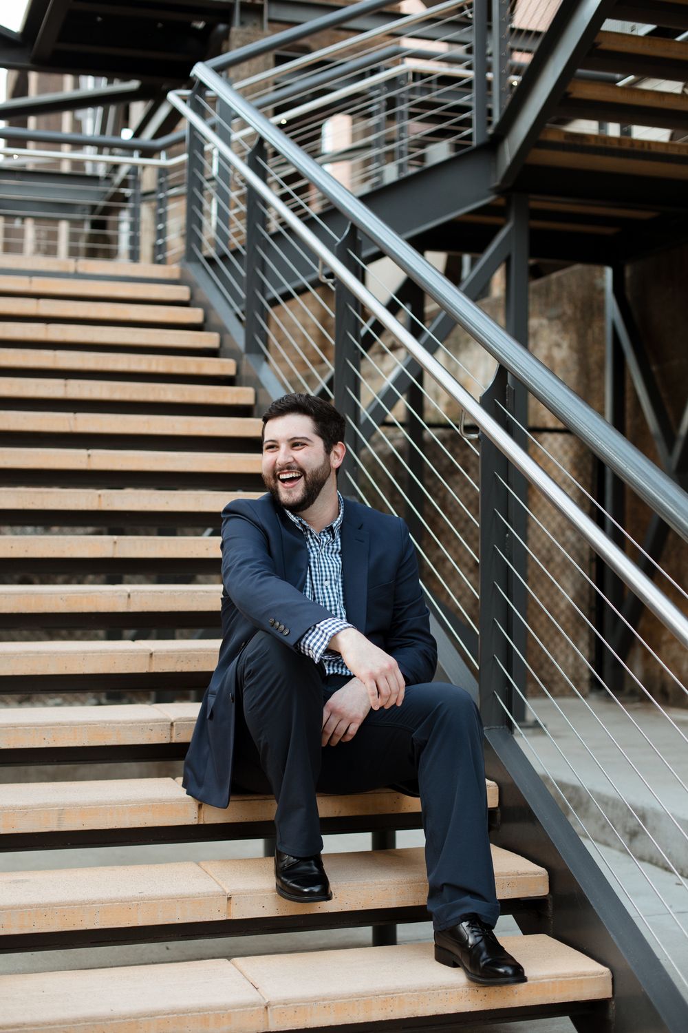 Casual portrait on wooden stairs with modern industrial metal railings.