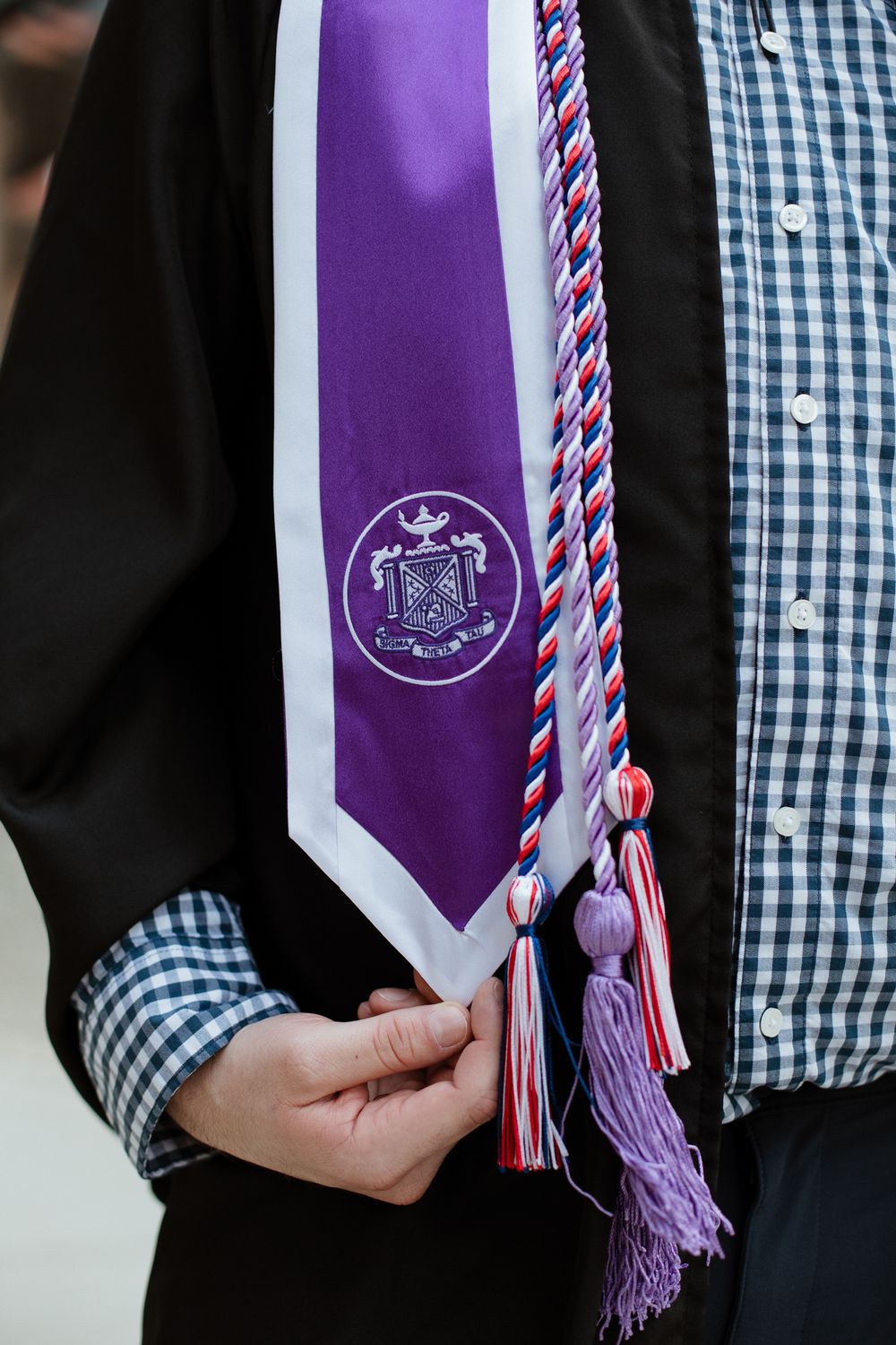 Close-up of purple graduation stole with tassels and university emblem.