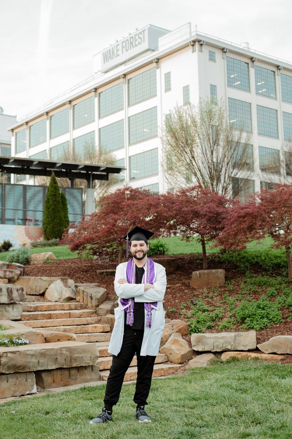 Graduate portraits taken in landscaped garden area with red maple trees and stone terraces.