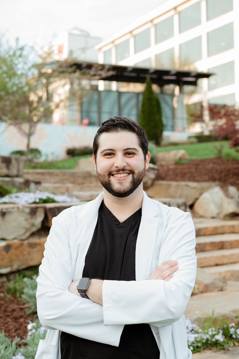 Professional portraits taken outdoors featuring white coat against modern building backdrop.