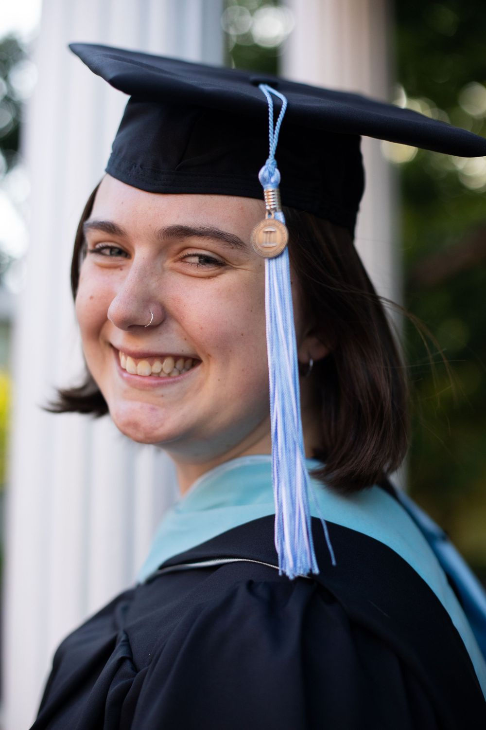 Close-up shots of a graduate wearing cap and gown with light blue tassel against white columns.
