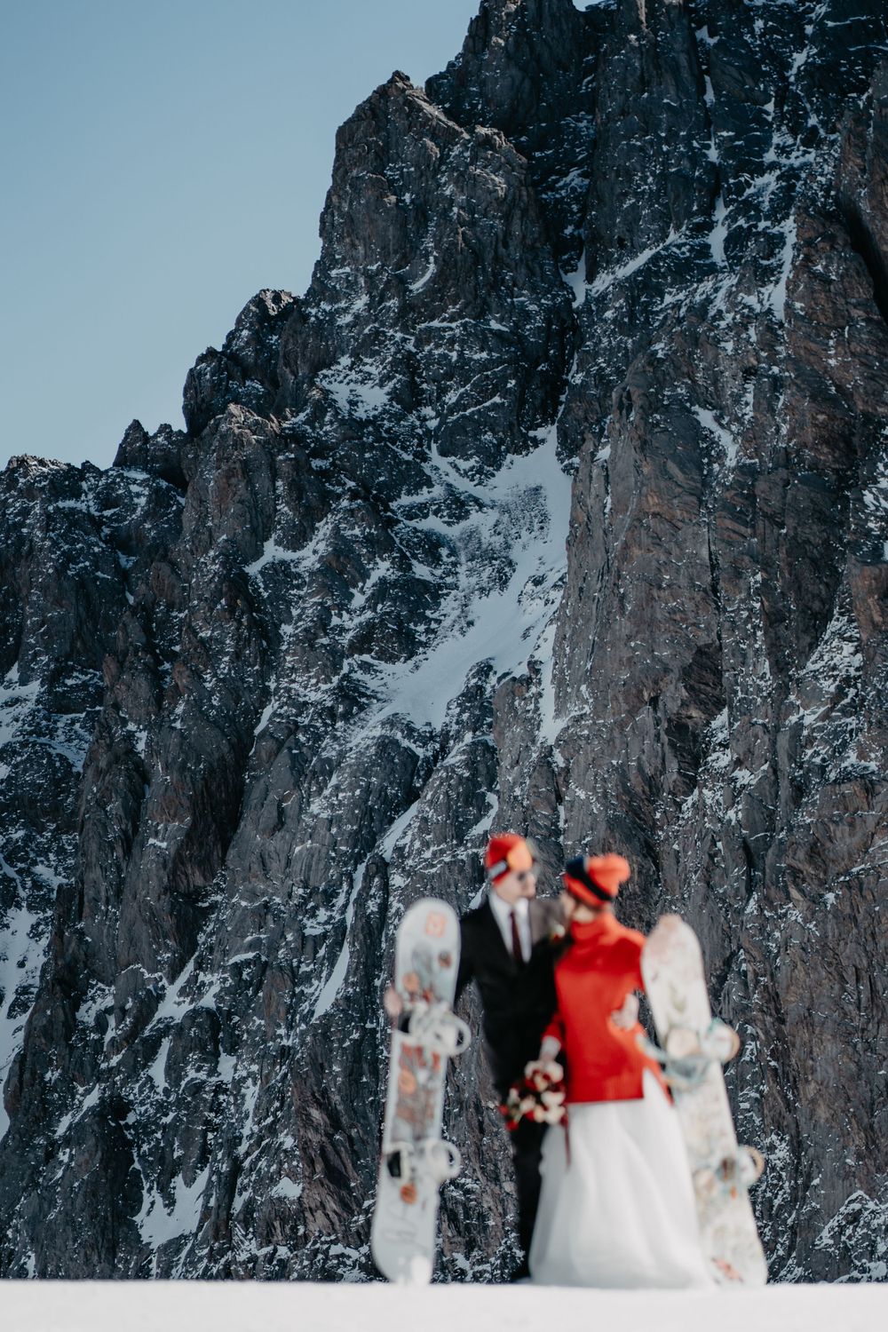 A couple in wedding attire standing by a towering mountain