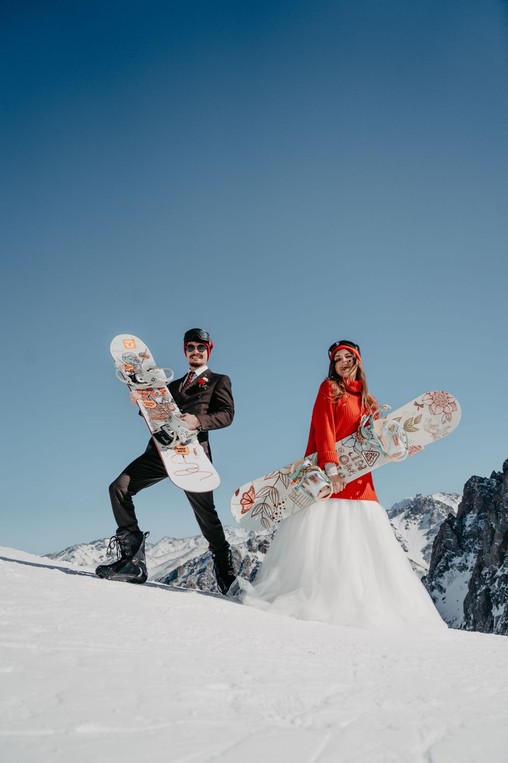 Bride and groom having fun together with their snowboards