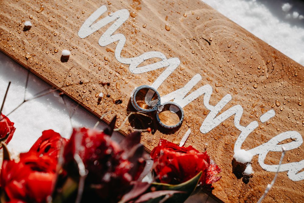 wedding rings and flowers on the wooden board