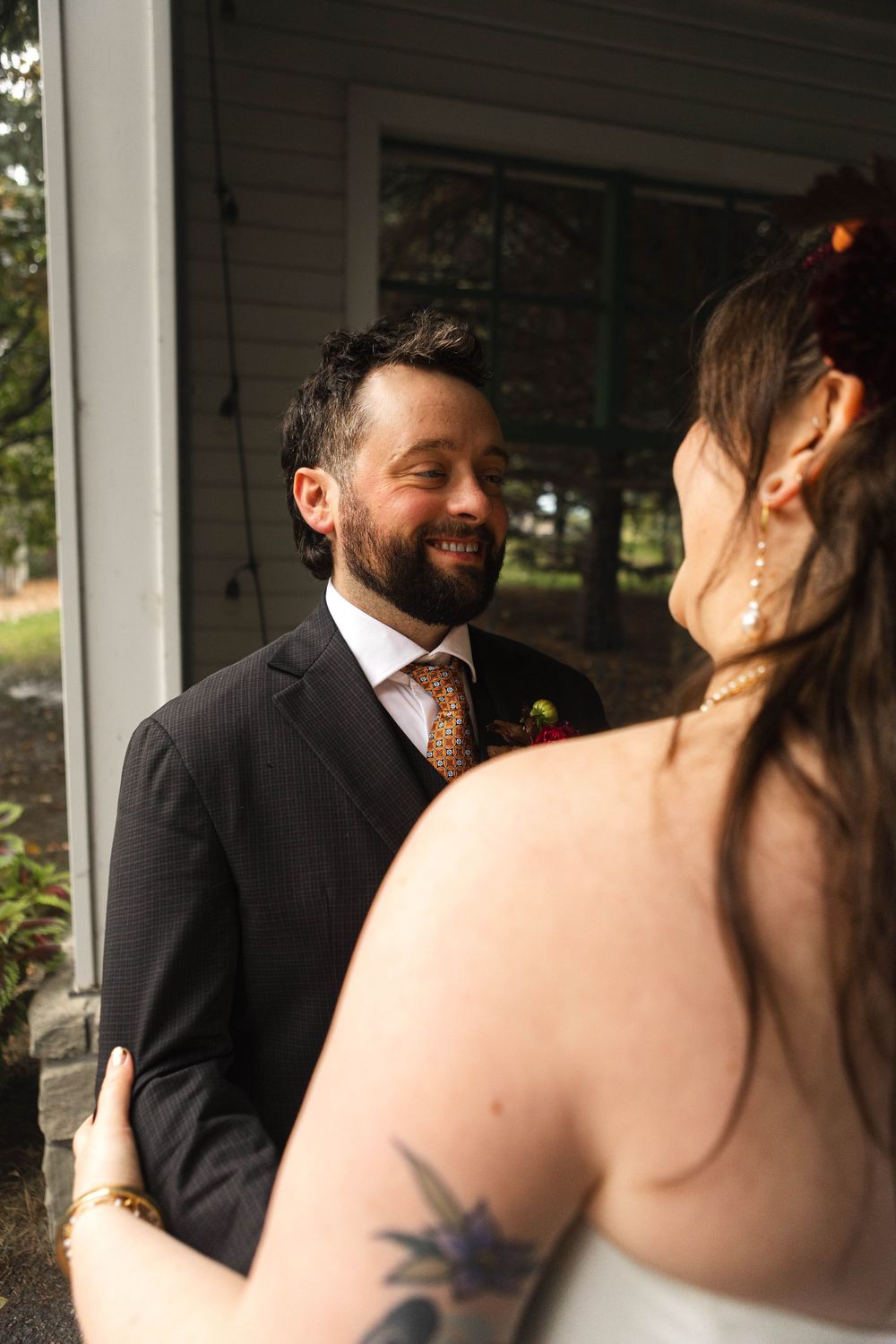 A couple shares joyful laughter during an intimate wedding moment on a covered porch.