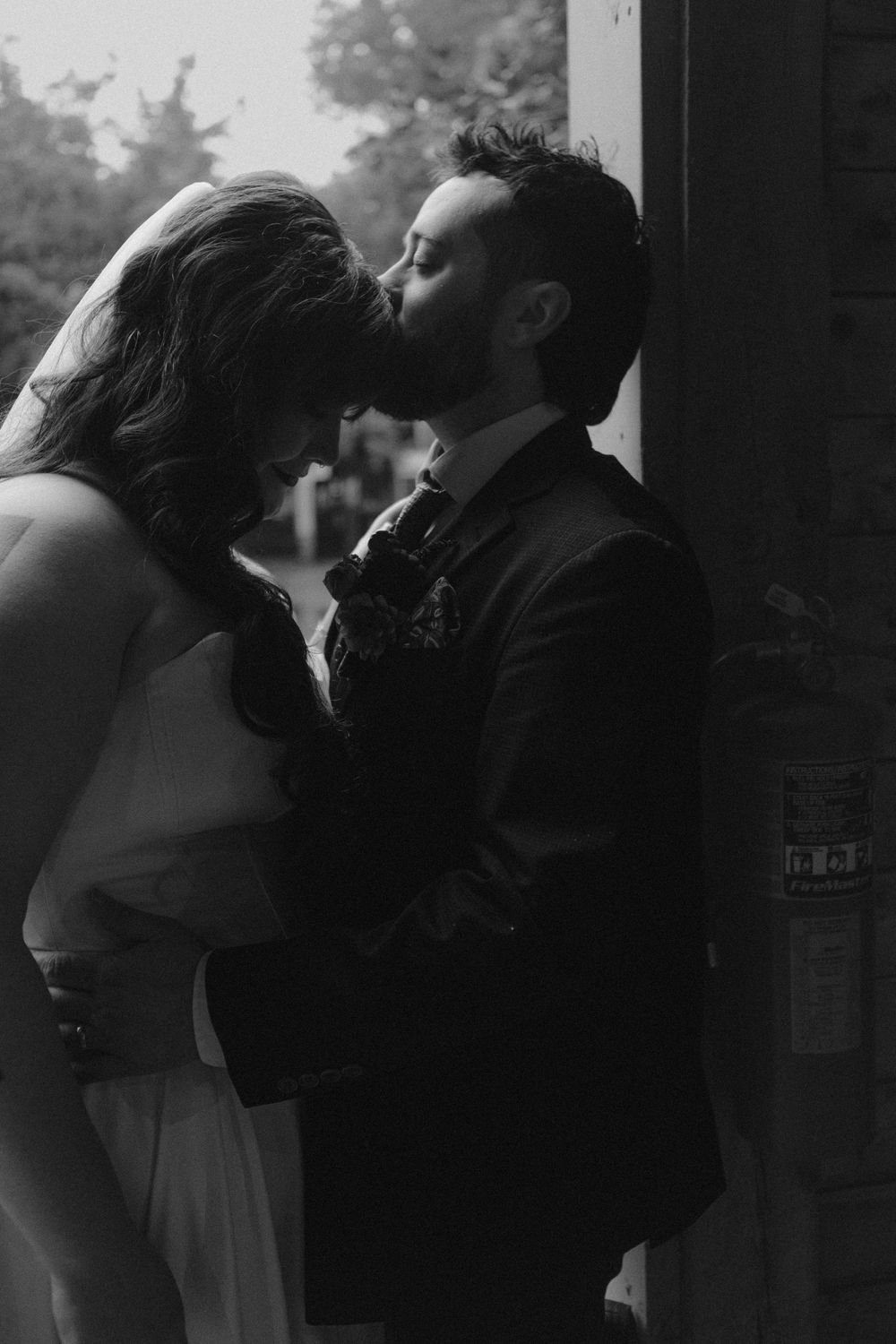 A romantic black and white silhouette of newlyweds embracing in a shadowy doorway.