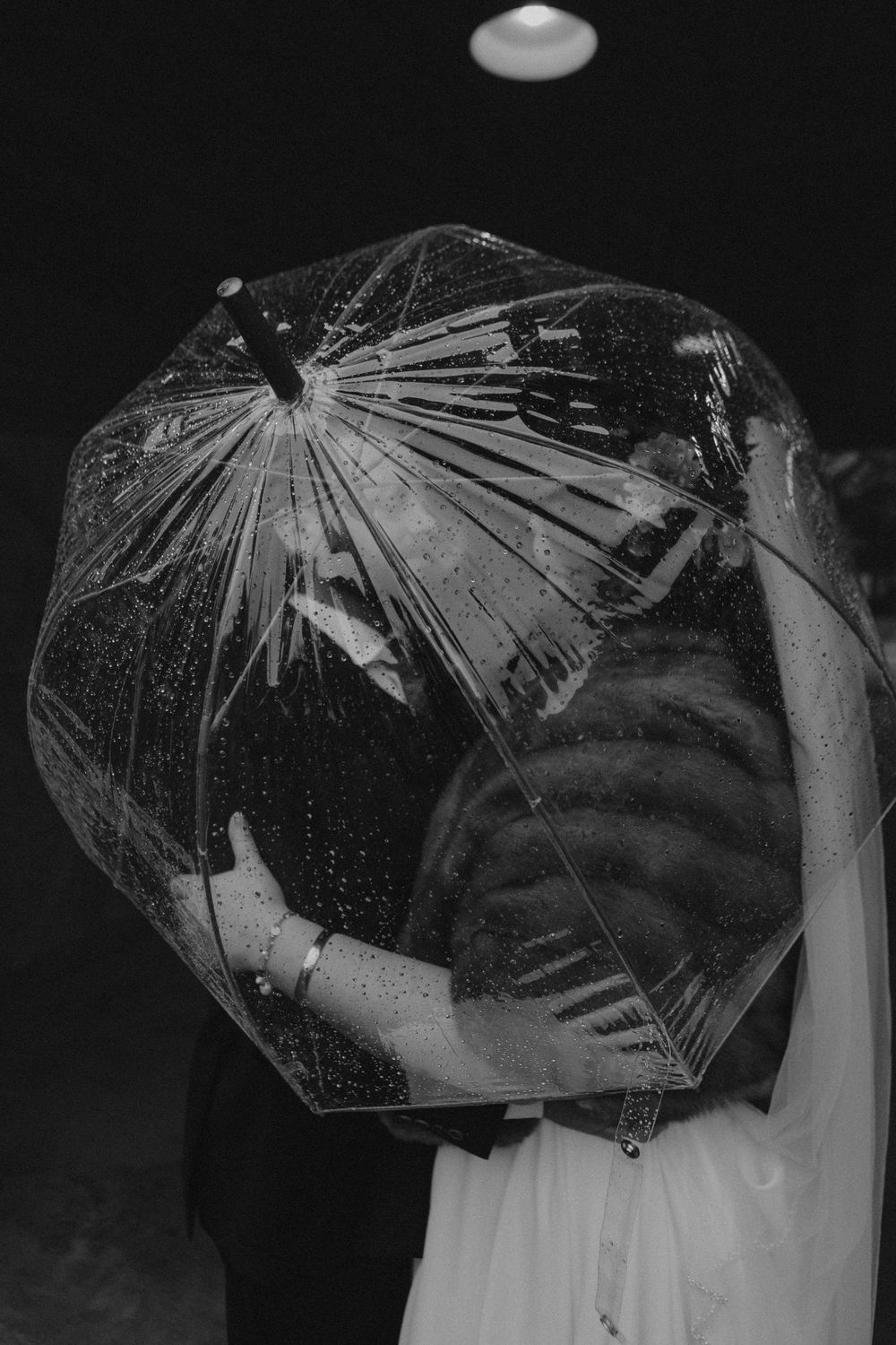 A sequence of black and white photos showing someone holding a clear umbrella in different positions against a dark background.
