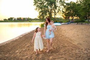 Family enjoying a sunset stroll along a sandy beach with golden light illuminating their path.