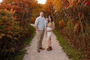 A couple walks along a scenic autumn path surrounded by vibrant orange and red fall foliage.