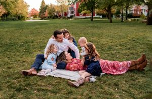 A family relaxes together on a picnic blanket in an autumn park.