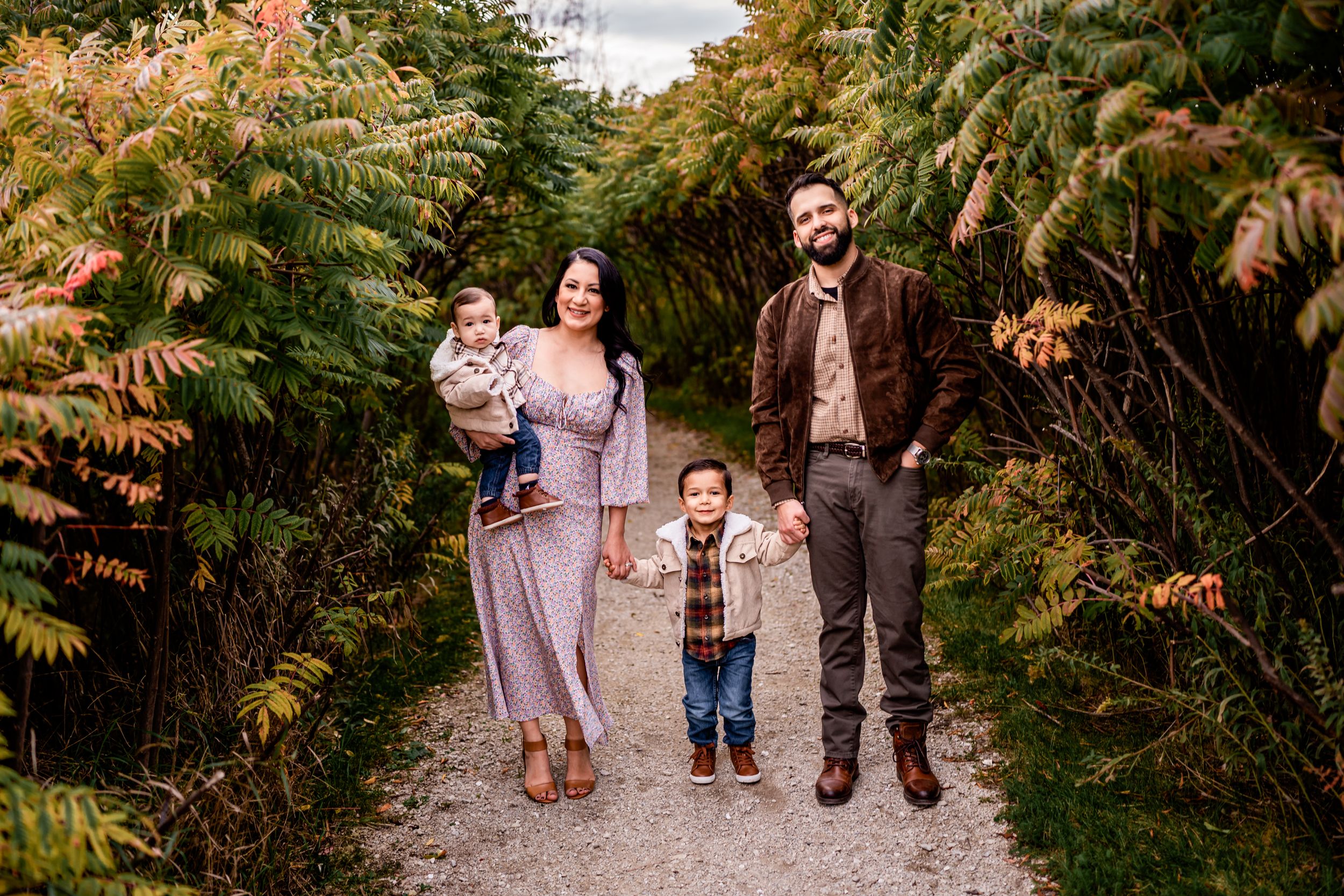 A family walks together on a nature path surrounded by lush greenery.