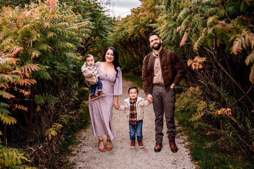 A family walks together on a nature path surrounded by lush greenery.